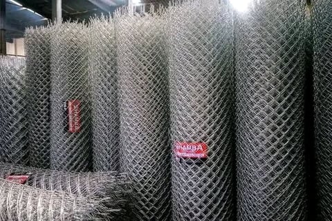 Rolls of chain-link fencing material stacked at an industrial warehouse