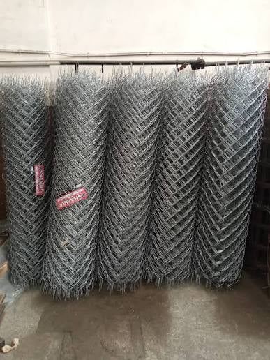Rolls of galvanized chain-link fencing material stacked and suspended from a horizontal bar