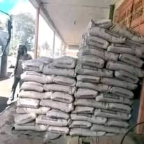 Stacked bags of cement or flour in a warehouse or storage facility with bright natural light from a window