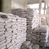 Stacks of white and gray tiles or building materials piled high in an indoor storage space or warehouse