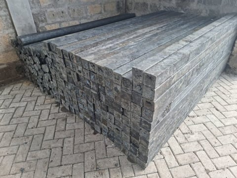 Concrete bench with dark textured stone block sides on a patterned brick ground next to a building