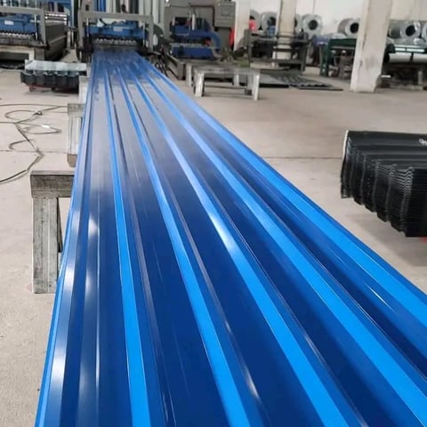 Long blue corrugated metal roofing panels lined up in an industrial factory warehouse setting
