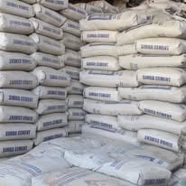 Stacked bags of cement or construction materials with printed labels stored in a warehouse