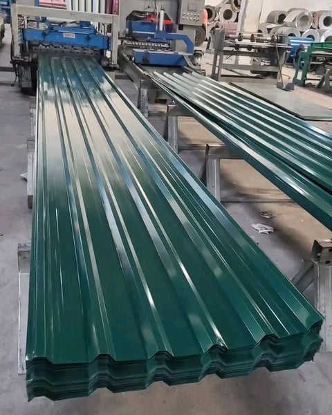 Industrial factory floor with green and teal corrugated metal roofing sheets manufactured by machinery